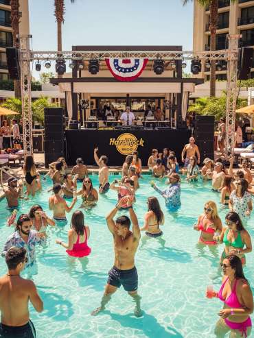 A lively pool party scene at a Hard Rock hotel, with many people in the pool and around the deck
