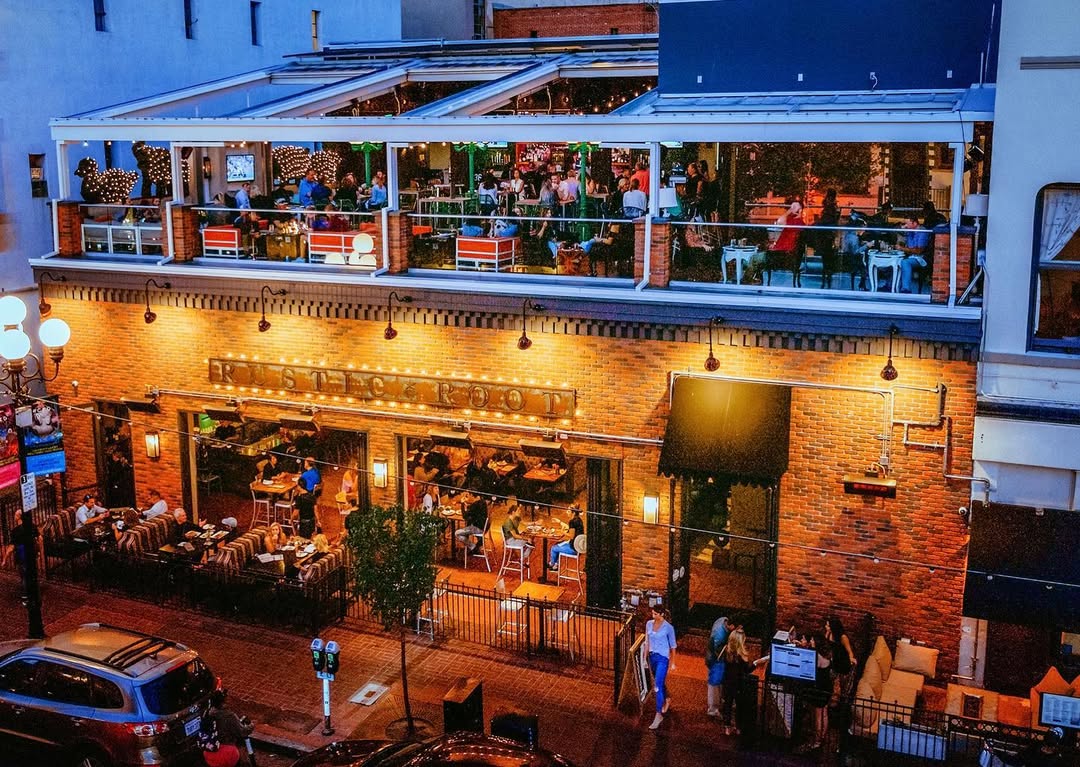 A high-angle exterior view of Rustic Root, a two-story restaurant in San Diego's Gaslamp Quarter, at night.